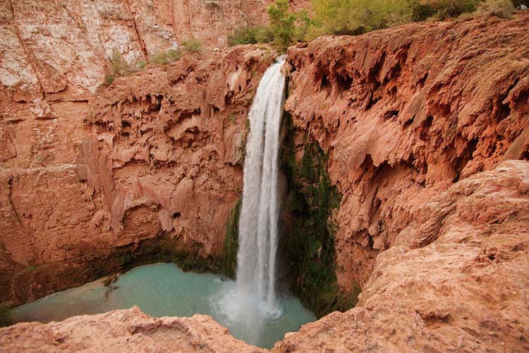 Havasu Falls: stunning turquoise waterfalls cascade down red rock cliffs in the Havasupai Reservation, Arizona. Havasu Falls is a stunning oasis in the Havasupai Reservation