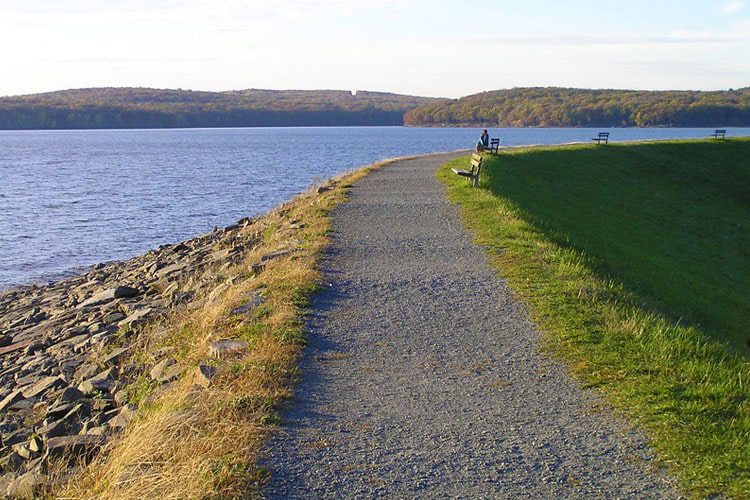 Top Destinations to Visit in Pennsylvania A serene view of Lake Wallenpaupack, with calm waters reflecting the vibrant autumn trees along the shoreline, creating a peaceful and picturesque lakeside scene.