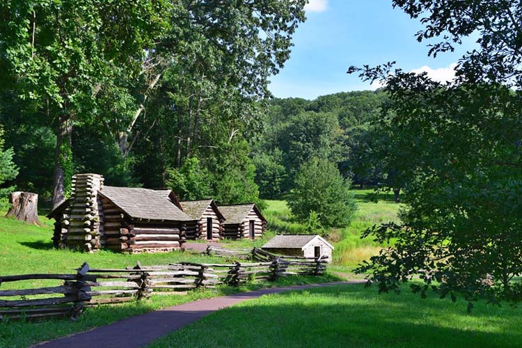 Scenic view of Valley Forge National Historical Park, featuring lush green fields, historic cabins, and monuments that commemorate the Revolutionary War. Popular Sites to Visit in Pennsylvania